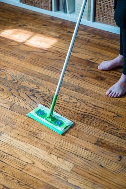 An adult male cleaning a glass window indoors, focusing on household chores and cleanliness.